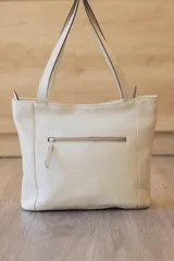 Cartera tipo tote de cuero vacuno negro con doble asa de hombro, panel superior liso y bolsillo exterior frontal con textura símil cocodrilo y costuras visibles en contraste.