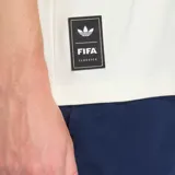 Remera de algodón de corte holgado, color blanco, con cuello redondo y mangas cortas. Presenta un pequeño logo de Adidas Originals bordado en el pecho y una etiqueta decorativa en el ruedo lateral.