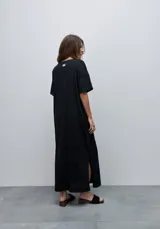Vestido midi negro de algodón con calce relajado, silueta recta, cuello redondo, mangas cortas amplias y tajos laterales.