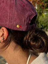 Gorra tipo dad hat color bordó con efecto lavado, con el logo de la marca bordado en hilo color crema en la parte frontal.