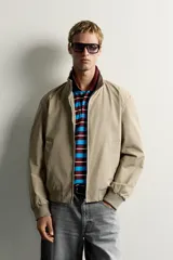 Cazadora relaxed fit de tejido ligero color azul marino, con cuello subido, manga larga y cierre frontal de cremallera. Cuenta con bolsillos frontales de vivo en la cadera y acabados en rib elástico en puños y cintura.