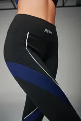 Calza deportiva larga negra con cintura alta, paneles laterales en azul y vivos blancos.