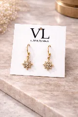 Caravanas colgantes de metal dorado con dije en forma de estrella de ocho puntas engarzada con strass.