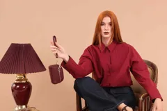 Monedero compacto de símil cuero color beige, con doble compartimento principal con cierre y un bolsillo frontal con cierre. Incluye una correa de mano lateral.