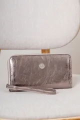 Billetera tipo sobre con correa de muñeca, confeccionada en cuero con textura de reptil en color marrón. Cuenta con cierre perimetral y placa metálica con el logo de la marca en el frente.