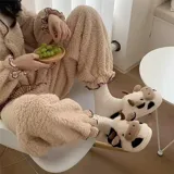 Pantuflas de peluche con diseño de vaca, confeccionadas en piel sintética suave. Cuentan con suela de goma antideslizante y diseño abierto en el talón.