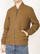 Campera tipo bomber color verde militar, confeccionada en 100% algodón. Cuenta con puños tejidos al tono, cuello y cintura elásticos, y cierre frontal metálico.