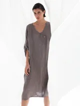 Vestido midi color visón de lino, con cuello en V, mangas 3/4 con botón para sujetar, corte evasé y dos botones decorativos en el frente.
