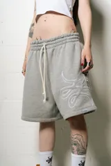 Bermuda estilo baggy de algodón color gris melange, con cintura elástica y cordón de ajuste de color crudo. Presenta un gran logo bordado en blanco en la pierna derecha.