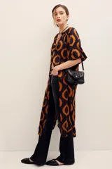 Vestido midi de viscosa color negro con estampado geométrico de círculos en tonos marrones y naranjas, de manga corta y corte recto con aberturas laterales.