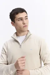 Buzo de punto con medio cierre frontal, cuello elevado y puños acanalados. Presenta un pequeño logo bordado en el pecho.