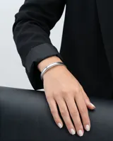 Pulsera tipo esclava rígida de acero, con diseño minimalista y bordes texturizados.