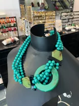 Collar corto de cuentas turquesas con apliques de resina verde, verde claro y negro.