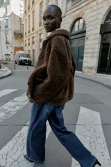 Chaqueta de cuello solapa y manga larga, con diseño de doble faz que combina tejido efecto ante y borreguillo. Cuenta con cierre frontal de botones y bolsillos delanteros.