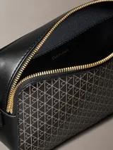 Cartera bandolera Calvin Klein de color negro, con estampado geométrico de monogramas en tono dorado, cierre superior de cremallera y correa ajustable.
