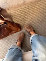 Zuecos de cuero marrón con diseño vintage, tachas plateadas y hebilla lateral.