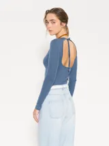 Remera de punto con textura suave, manga larga y escote redondo. Presenta un diseño ajustado al cuerpo con espalda abierta y largo a la primera cadera.