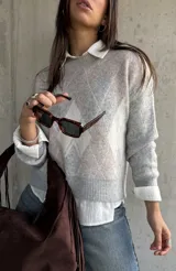 Sweater de punto con diseño de rombos en tonos gris y beige, cuello redondo, mangas largas y puños acanalados.