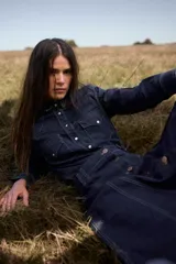 Camisa de jean de corte clásico estilo western, confeccionada en denim azul oscuro con pespuntes contrastantes. Presenta cuello camisero, bolsillos frontales con solapa y cierre de botones metálicos a presión.