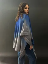 Ruana larga de lana merino color gris con cuello plisado de fieltro. Diseño degradado con terminación en flecos.