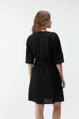 Vestido corto beige con escote en V, mangas cortas amplias y cintura elastizada con lazo ajustable.