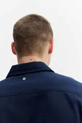 Camisa rústica de manga larga color gris oscuro, con cuello clásico, cierre frontal con botones y un bolsillo aplicado en el pecho.