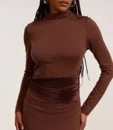 Vestido midi marrón con cuello alto y mangas largas. Presenta un detalle de encaje en la parte trasera y una faja de terciopelo en la cintura.