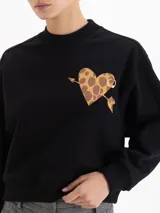 Buzo negro de corte regular, confeccionado en rústico de algodón con cuello redondo, puños y cintura en ribb. Presenta una estampa frontal de un corazón con diseño de animal print atravesado por una flecha.
