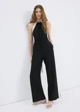 Jardinera larga de lino y viscosa, color negro con detalles de rayas blancas en contraste en los laterales. Cuenta con cuello halter, sin mangas, diseño recto, dos bolsillos laterales y cordón ajustable en la cintura.