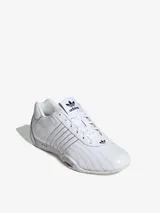 Zapatillas Adidas Adiracer Lo color blanco, inspiradas en los coches de carreras. Confeccionadas en cuero y material sintético, con las tres tiras características de la marca en los laterales.