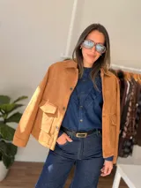 Chaqueta de estilo clásico con acabado efecto gamuza, confeccionada en algodón. Presenta cierre frontal con botones, cuello camisero y dos bolsillos delanteros con solapa. Posee interior forrado y corte recto.