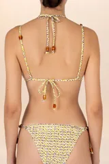 Top de bikini con estampado de leopardo en tonos amarillo y violeta. Tiene forma triangular, tirantes finos con cuentas y cierre con lazo.