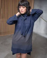 Vestido azul con estampado a cuadros, cuello con lazo y corte recto holgado con aberturas laterales.