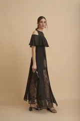 Vestido largo negro con hombros descubiertos, volados en el pecho, mangas cortas y paneles de encaje transparente en la falda.