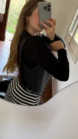 Chaleco negro de ecocuero con tachas doradas.