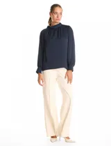 Blusa satinada de cuello alto con frunces, detalle de lazo lateral y cierre de botones. Presenta mangas largas estilo balloon con puños ajustados.