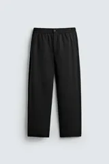 Pantalón negro de corte regular fit, confeccionado en tejido con viscosa. Cuenta con cintura elástica, bolsillos delanteros y detalle de bolsillos traseros de vivo. El cierre frontal es con cremallera y botón.
