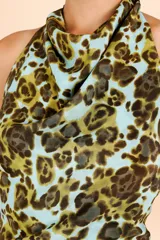 Vestido corto con escote halter y cuello drapeado, de silueta fluida y corte recto. Presenta un estampado orgánico en tonos verdes y celestes.