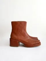 Bota de caña media color óxido, confeccionada en cuero, con plataforma y taco cuadrado texturizado, punta cuadrada y cierre lateral.
