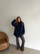 Pantalón tipo oxford de tiro alto con estampado animal print de jirafa en tonos azul y beige. Presenta un corte ajustado en la parte superior y acampanado en el ruedo.