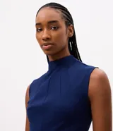 Blusa azul marino sin mangas de la marca Cortelle, con cuello alto, recortes estructurales y dobladillo estilo peplum asimétrico.