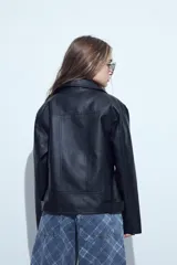 Campera biker de cuero sintético en color negro, con cierre frontal diagonal, bolsillos laterales con cierre y cinturón ajustable en la cintura con hebilla metálica.