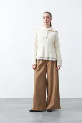 Sweater de tejido de punto color azul marino, con cuello polo amplio y cierre frontal con tres botones metálicos. Presenta mangas largas levemente acampanadas y un diseño de silueta relajada con aberturas laterales en el ruedo.