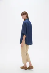 Camisa azul de jean de manga corta, corte holgado, con cuello camisero y cierre frontal con botones.