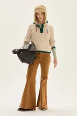 Sweater de punto con diseño de ochos en color crudo, con cuello polo y tapeta de botones en contraste verde. Presenta bordado en el pecho, puños y ruedo acanalados con detalles de rayas en verde.