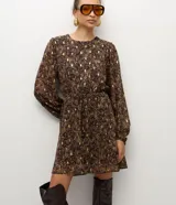 Vestido corto de chiffon con estampado paisley en tonos marrones y detalles metalizados dorados. Presenta mangas largas con puños elásticos, cuello redondo y falda con caída fluida.