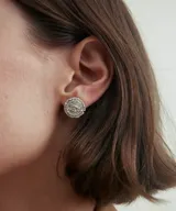 Aros tipo botón plateados con diseño floral texturizado.