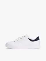 Zapatillas de tenis minimalistas Tommy Hilfiger, confeccionadas en piel napa blanca con suela gruesa tipo cupsole. Presentan un diseño de corte bajo con cordones, detalle de panel azul marino en el talón y logo metálico de la marca en el lateral.