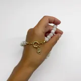 Collar de cuentas de piedra de la luna de 8 mm, con nudos de hilo color caramelo entre cada cuenta. Presenta un cierre frontal de argolla tipo mosquetón y un dije en forma de corazón con baño de oro.