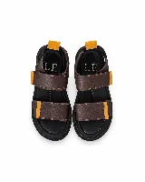 Sandalias de cuero marrón con tiras anchas, detalles en mostaza y suela plana acolchada con cierre de velcro.